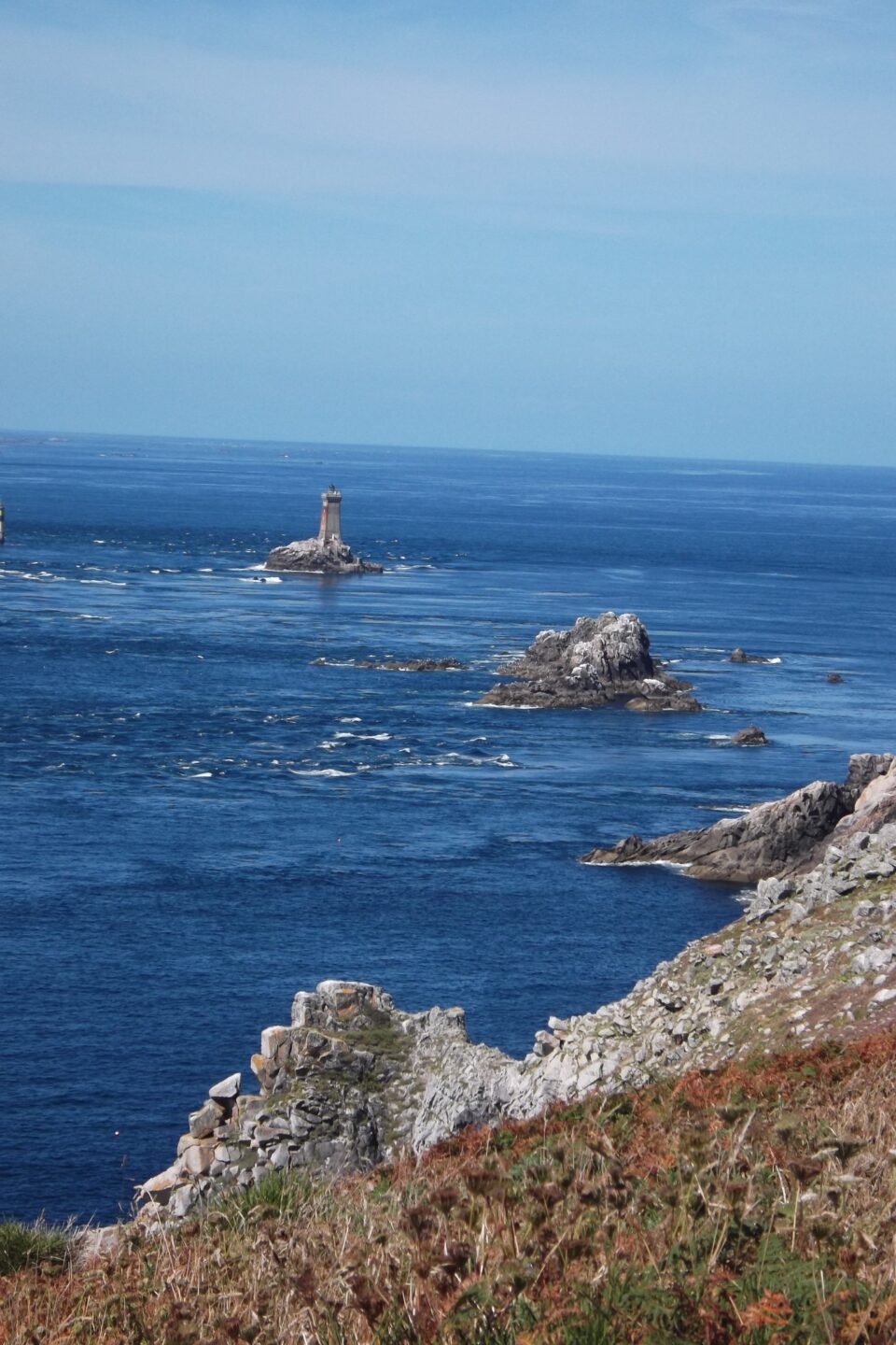 Promontorio che si affaccia sull'oceano, faro in lontanza